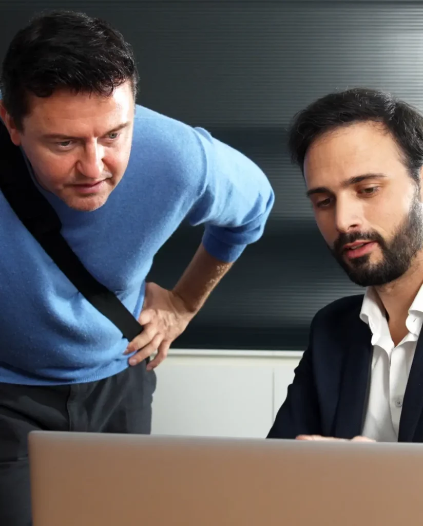 Flottenmanager und Mitarbeiter sehen sich das Charging4Fleets-Portal am Laptop an.