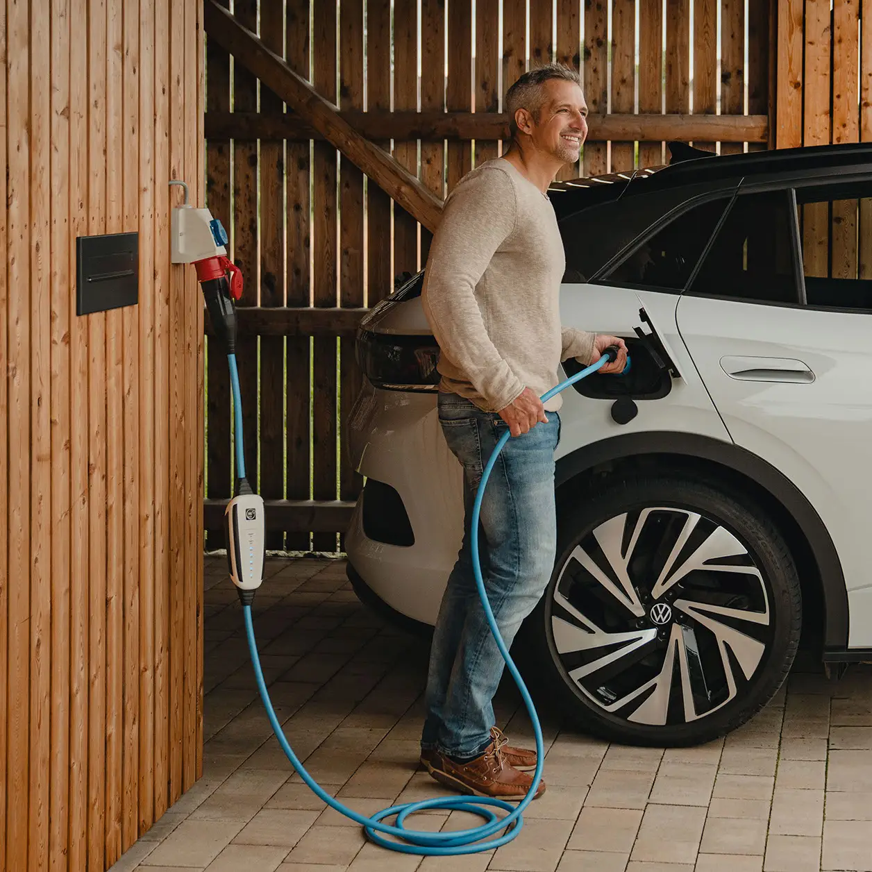 Mann steckt gerade die Steckeinheit des NRGkick in die Ladebuchse seines E-Autos.