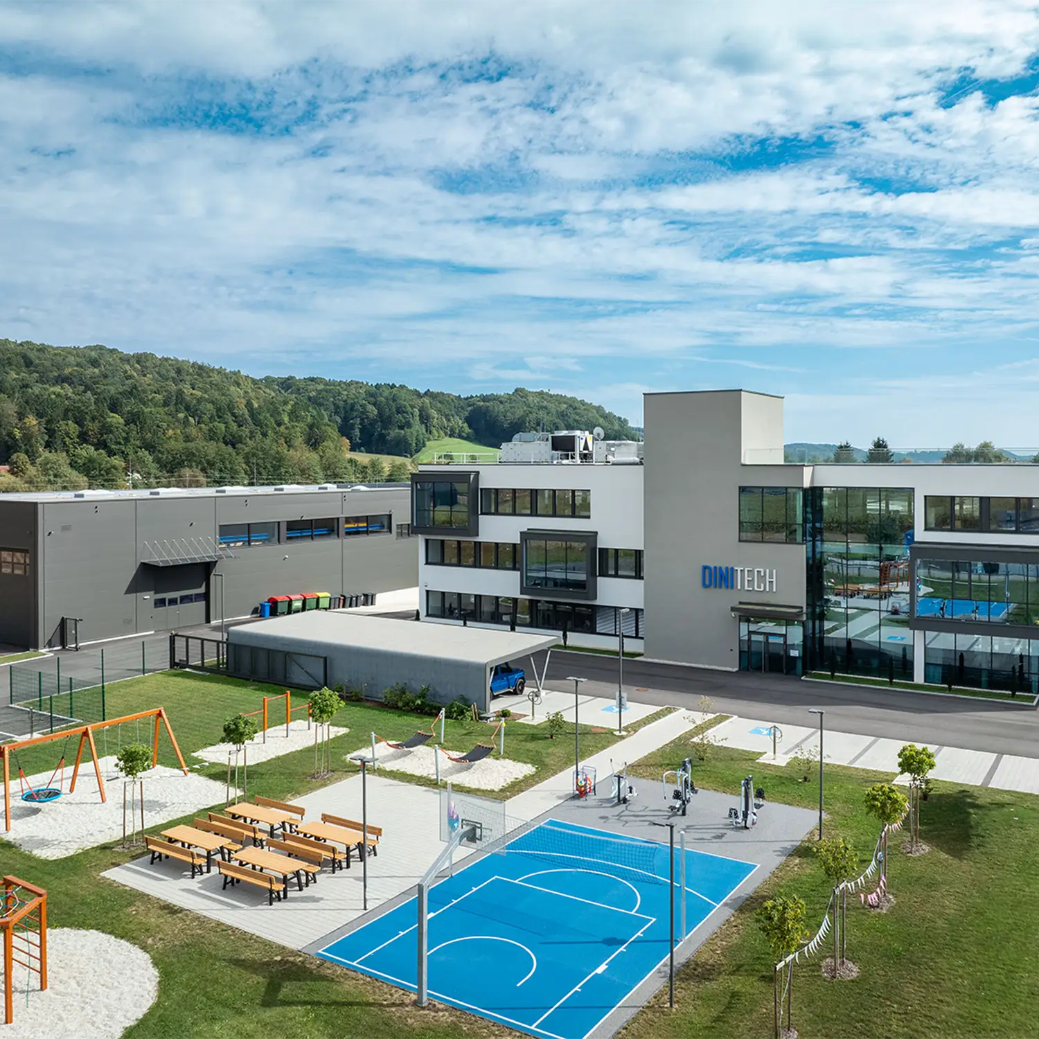 Grüner Außenbereich des Kompetenzzentrums DiniTech mit Sportanlage.